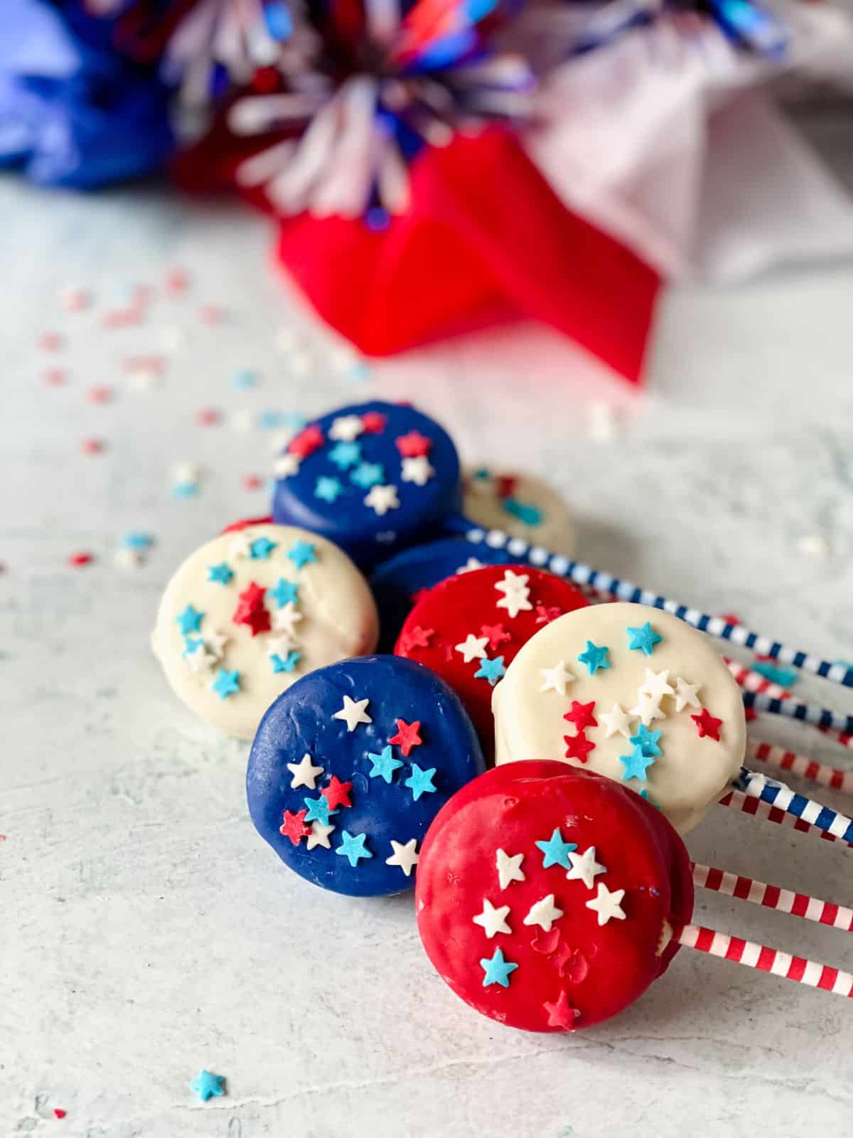 red white and blue dipped oreo cookies with striped handles on white table