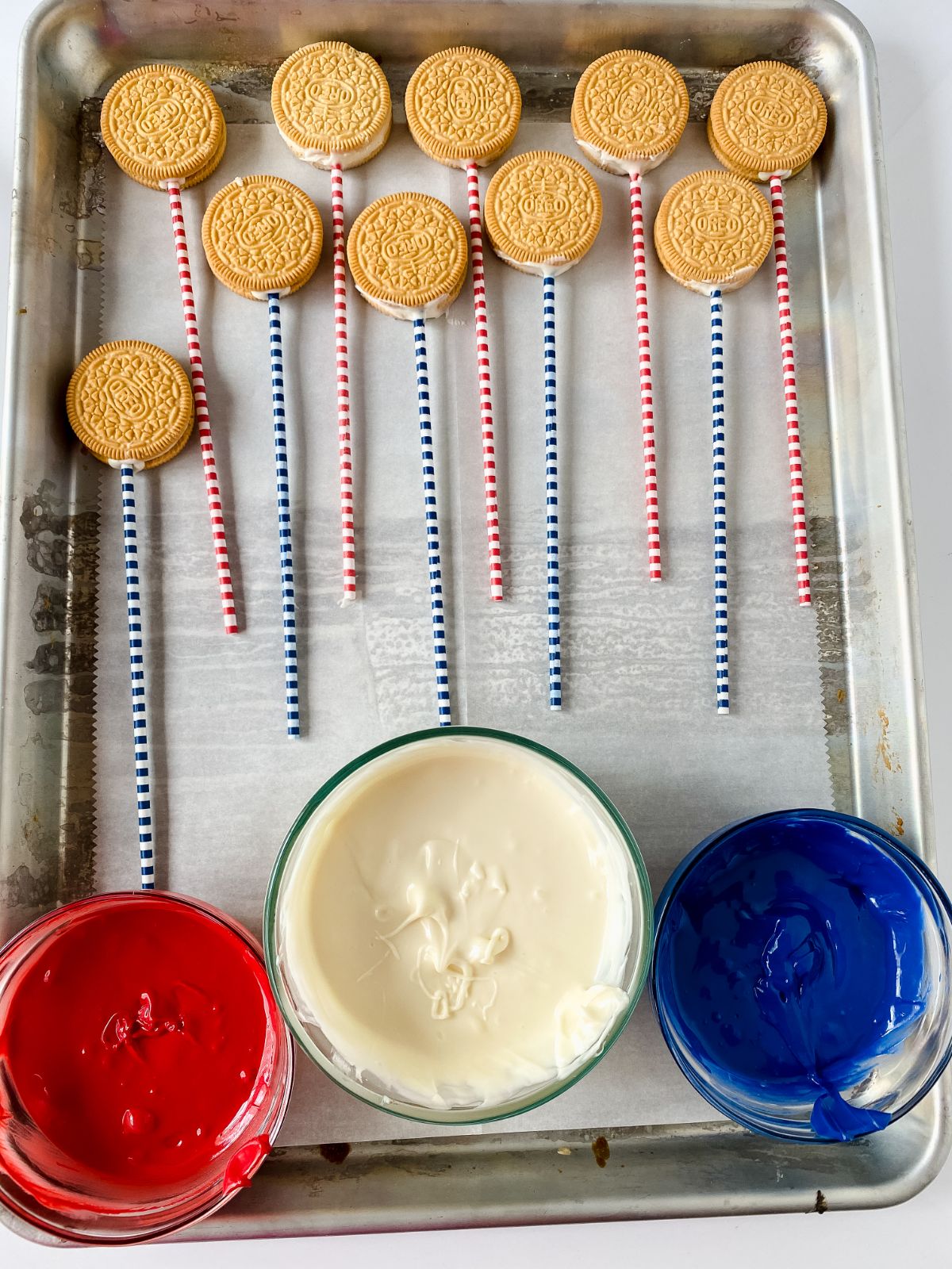tray of cookies on striped straws by bowls of patriotic chocolate melted