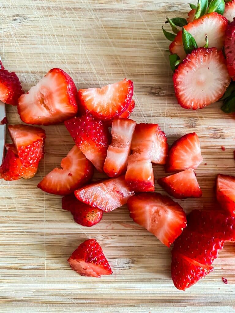 strawberries sliced on wood cutting board